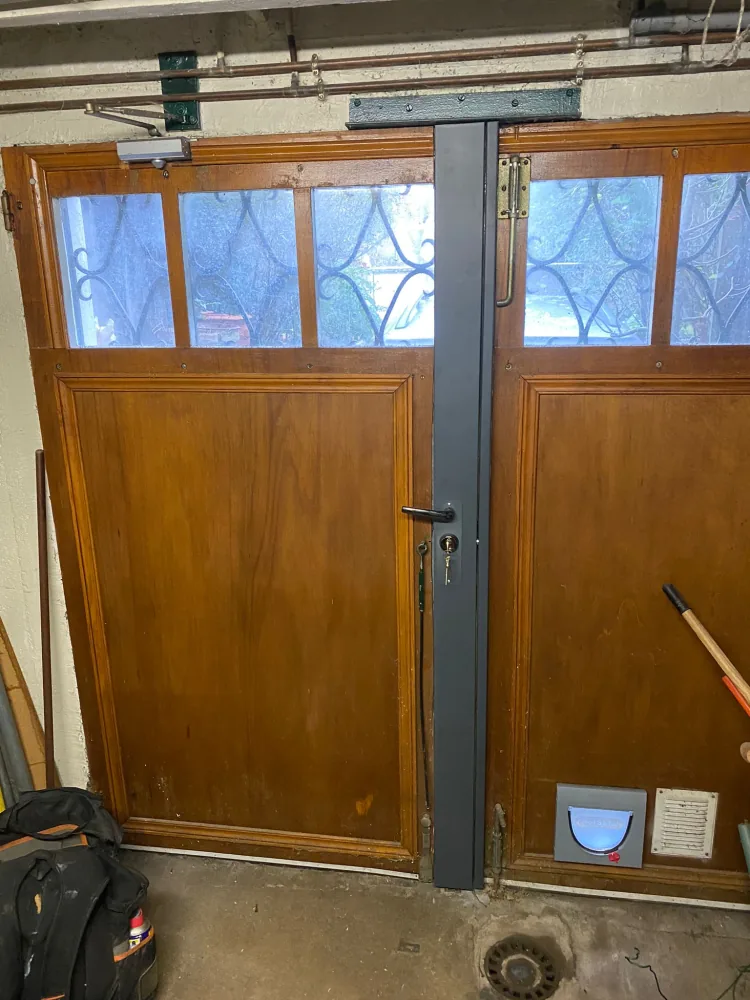 Serrure carénée Picard anthracite posée sur une double porte en bois vernis donnant sur un parking