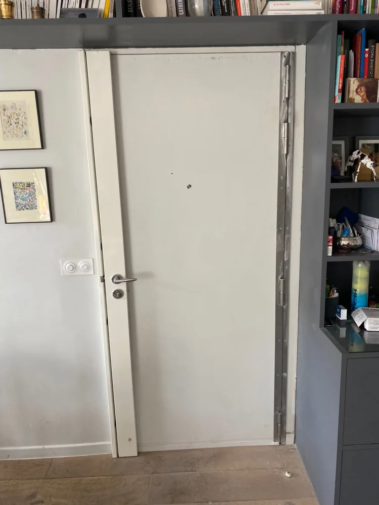 Barre de pivot acier à quatre paumelles posée côté charnières d'une porte blindée blanche